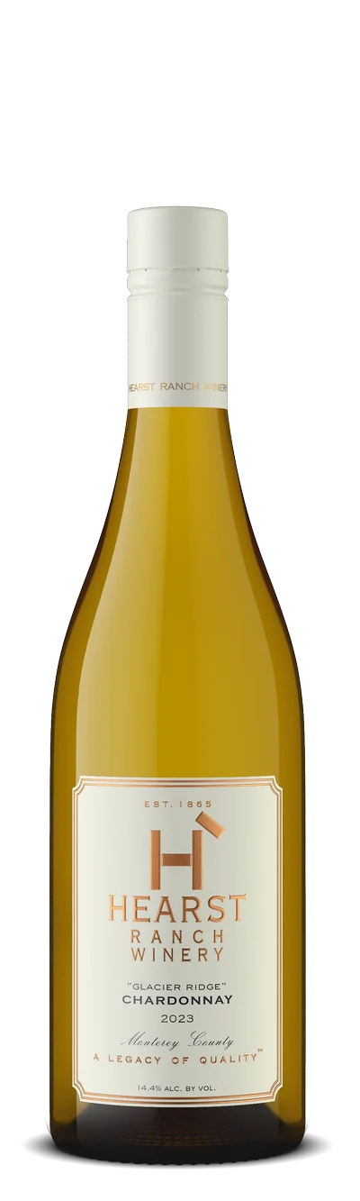 A bottle of Hearst Ranch Winery Chardonnay 2023 with a white label and gold trim, featuring the winery's logo and details about the wine. TheCentralCoast.com